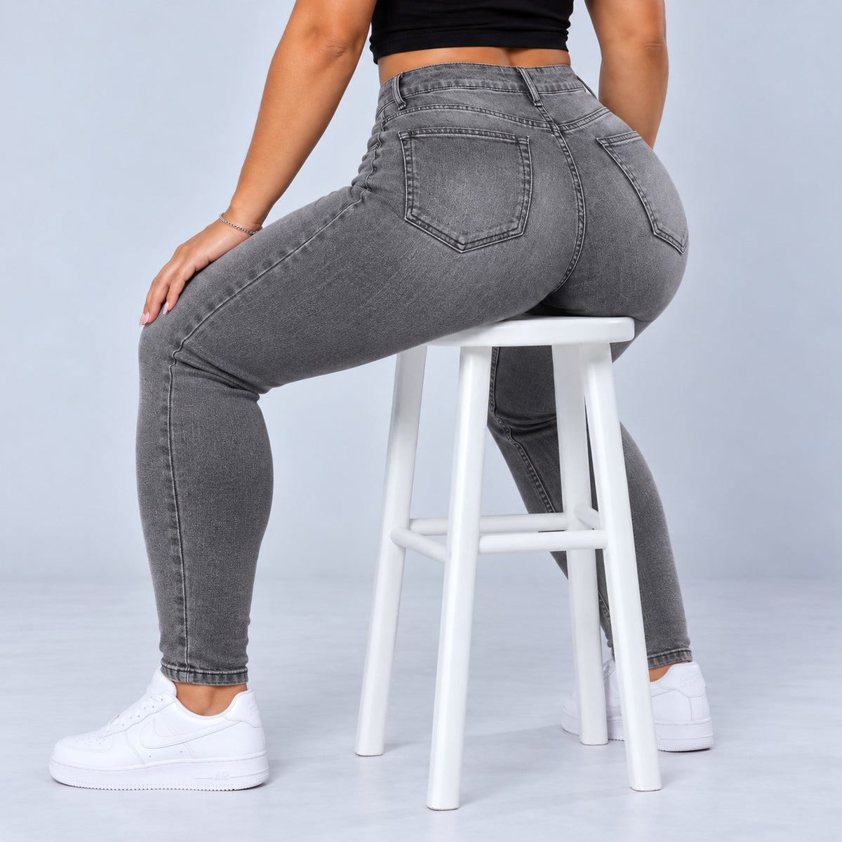 Sculpt Skinny BBL jean in grey, seated on a stool