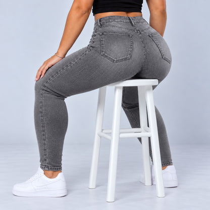 Sculpt Skinny BBL jean in grey, seated on a stool