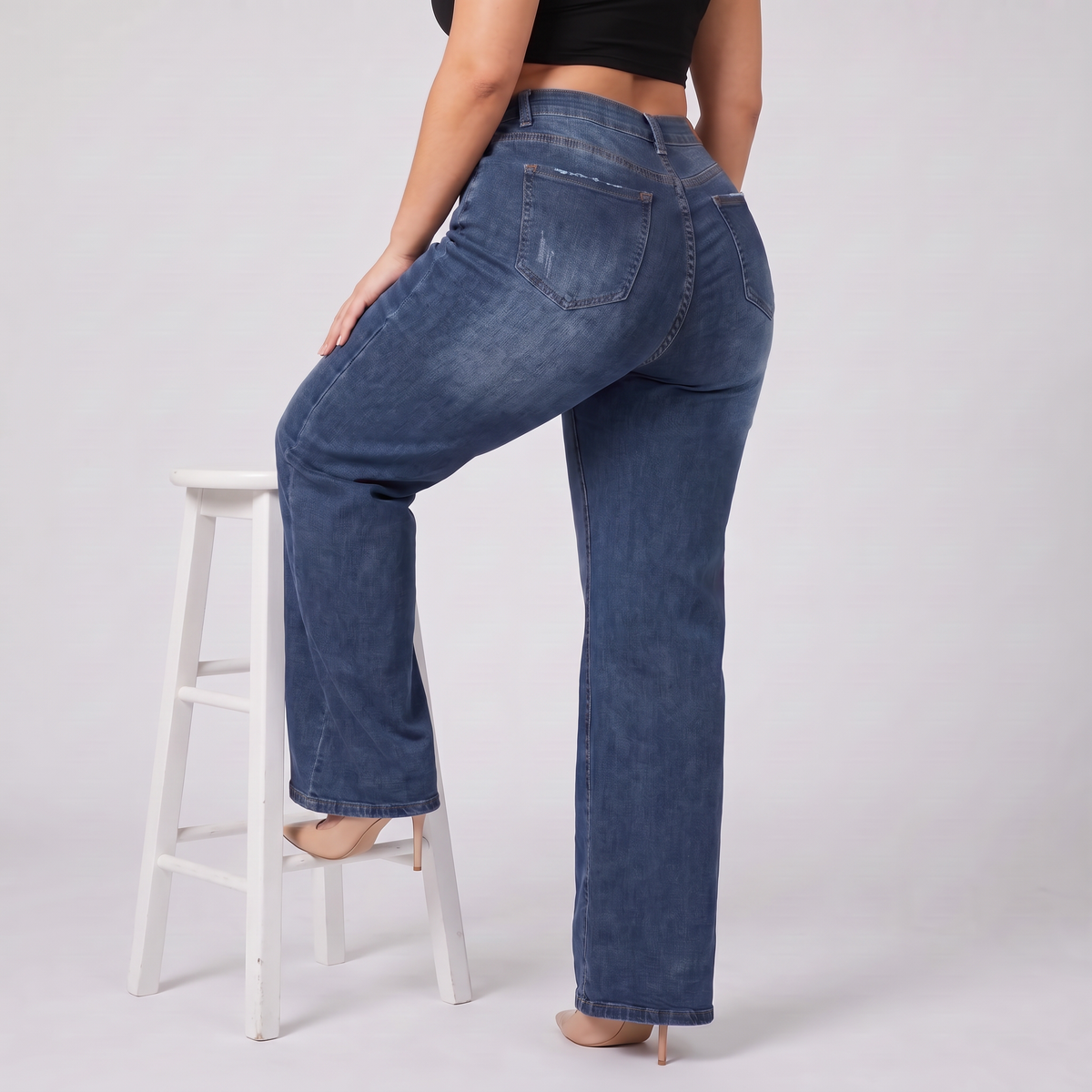 Sculpt Wide Leg BBL jean in dark blue, seated on a stool