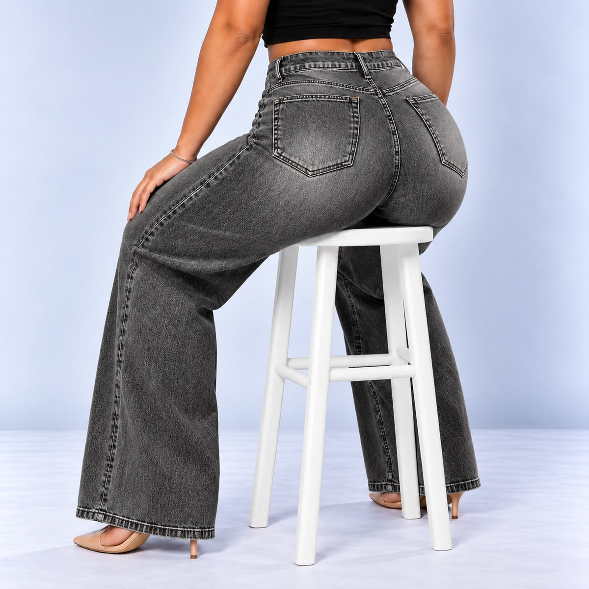 Sculpt Wide Leg BBL jean in grey, seated on a stool