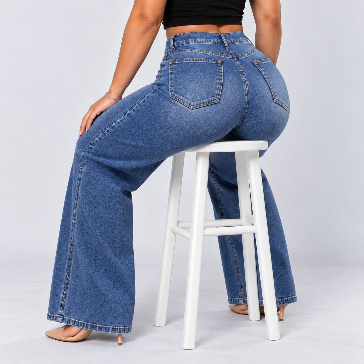 Sculpt Wide Leg BBL jean in mid blue, seated on a stool